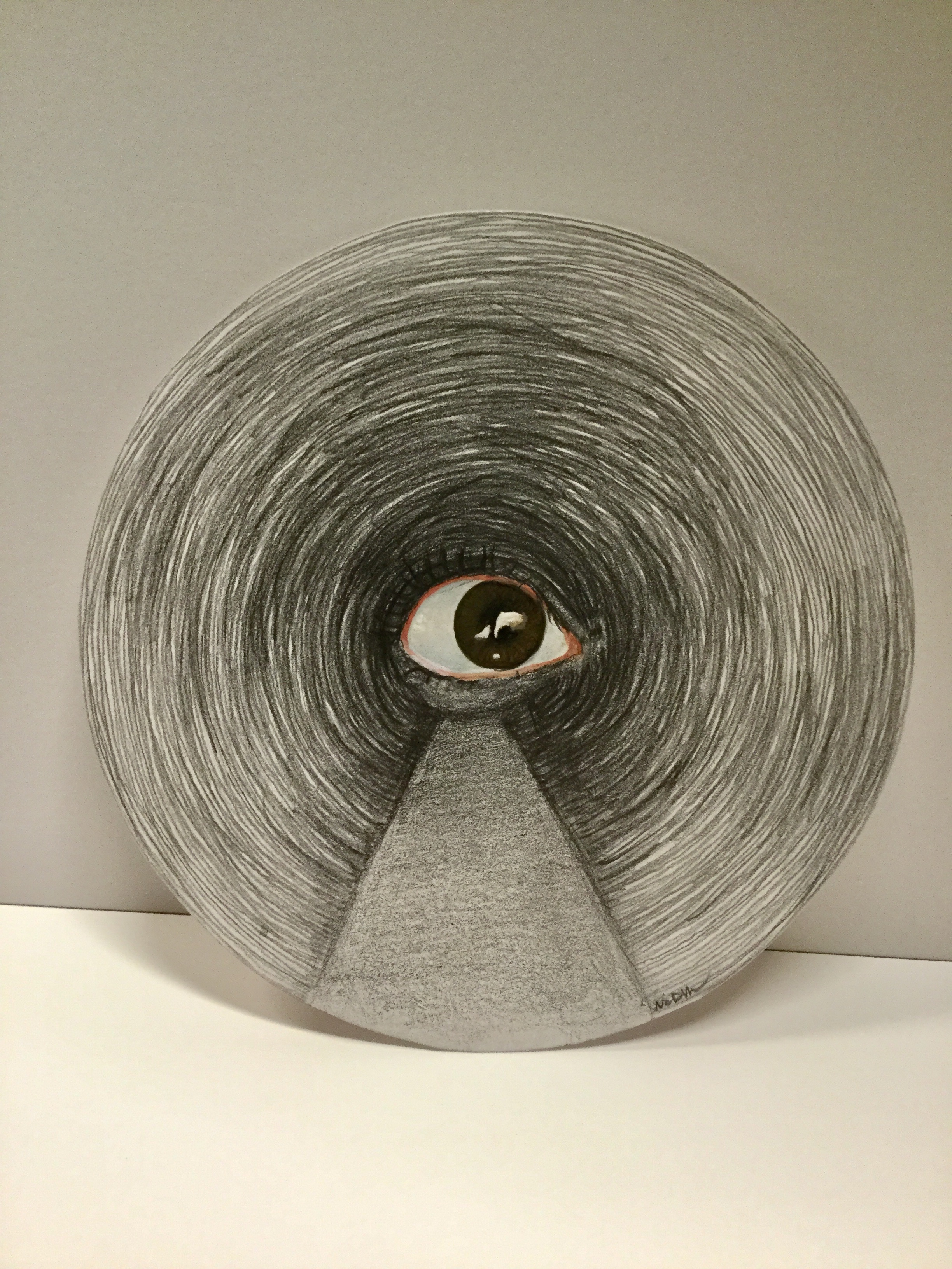 Gouache painting of an eye with graphite sketchy circles and shading around it. Cut into a circle.